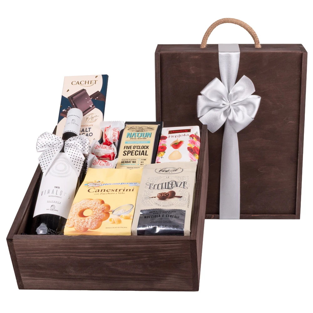 Zestaw prezentowy w eleganckiej ciemno-brązowej drewnianej skrzynce przewiązanej kokardą z czerwonym winem, delikatesami i możliwością dodania graweru lub personalizowanej papeterii – idealny prezent na imieniny dla koleżanki.